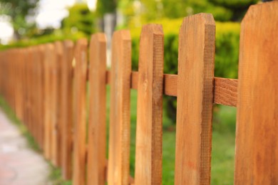 Photo of Closeup view of small wooden fence near green bush outdoors, space for text