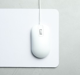 Photo of Wired computer mouse and pad on light grey background, flat lay. Space for text