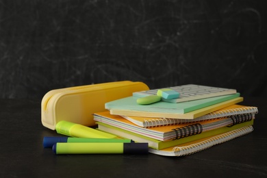 Photo of Different school stationery on stone table near blackboard. Back to school