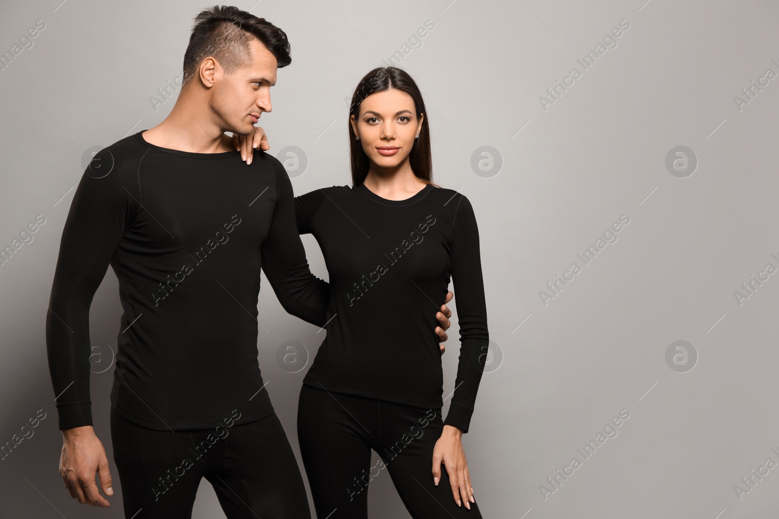 Photo of Couple wearing thermal underwear on grey background. Space for text