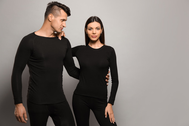 Couple wearing thermal underwear on grey background. Space for text