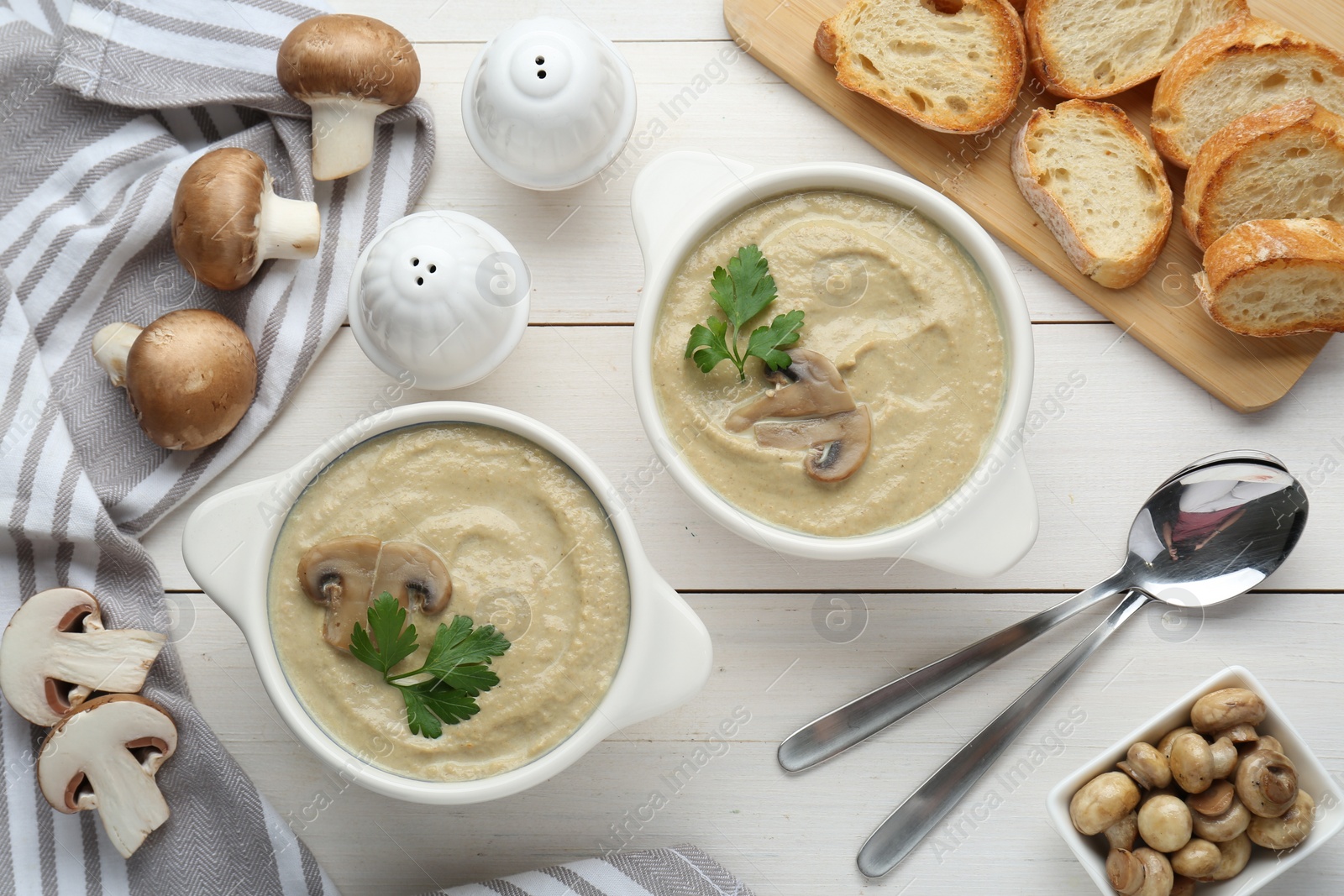 Photo of Delicious mushroom cream soup with parsley served on white wooden table, flat lay