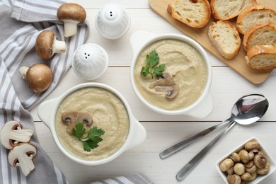 Delicious mushroom cream soup with parsley served on white wooden table, flat lay