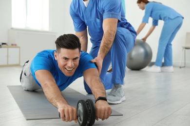 Professional physiotherapist working with male patient in rehabilitation center