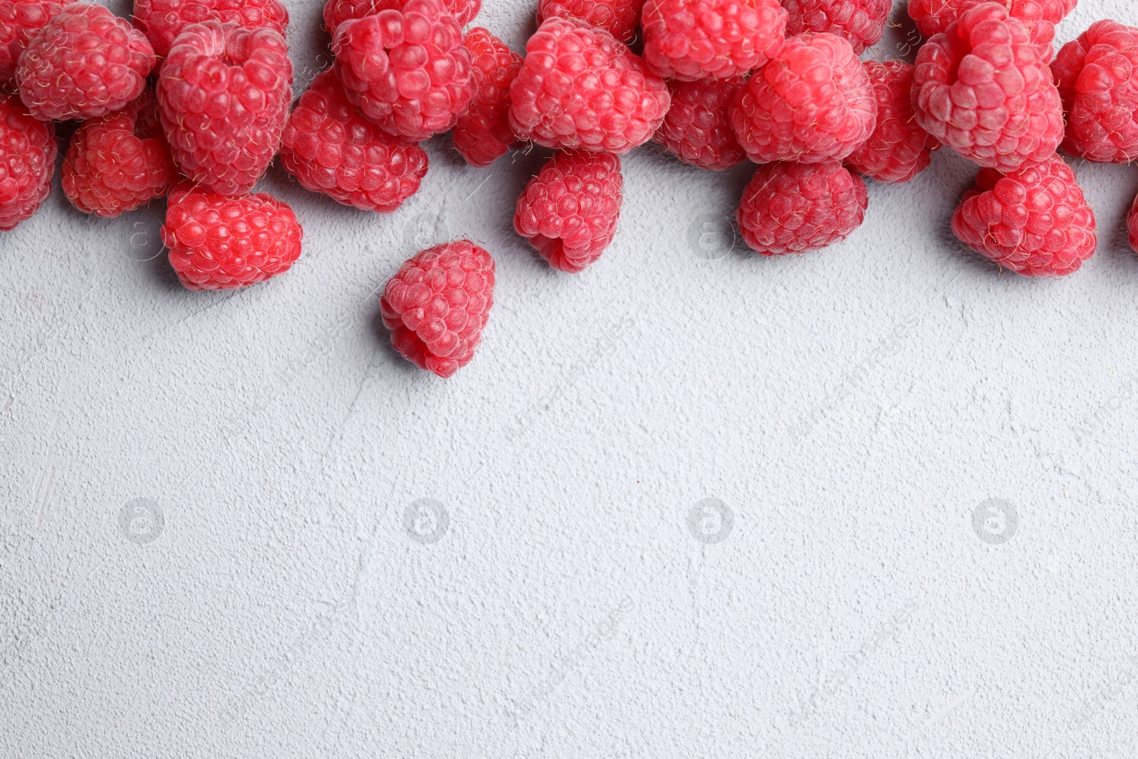 Photo of Fresh ripe raspberries on light grey table, top view. Space for text