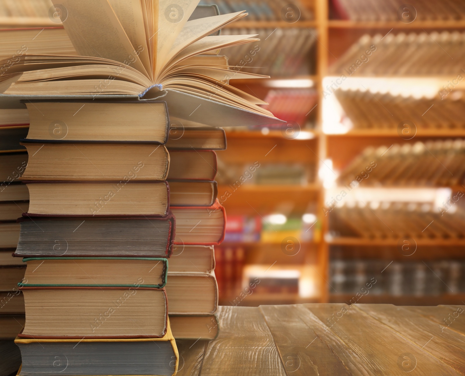 Image of Stacks of different books on wooden table in library, space for text