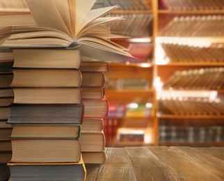 Image of Stacks of different books on wooden table in library, space for text