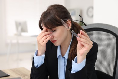 Overwhelmed woman with glasses suffering in office