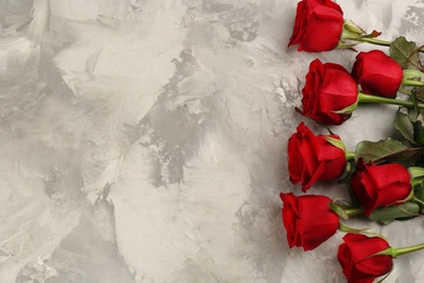 Beautiful red roses and space for text on light grey background, flat lay. Valentine's Day celebration