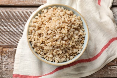 Photo of Delicious pearl barley in bowl on wooden table, top view