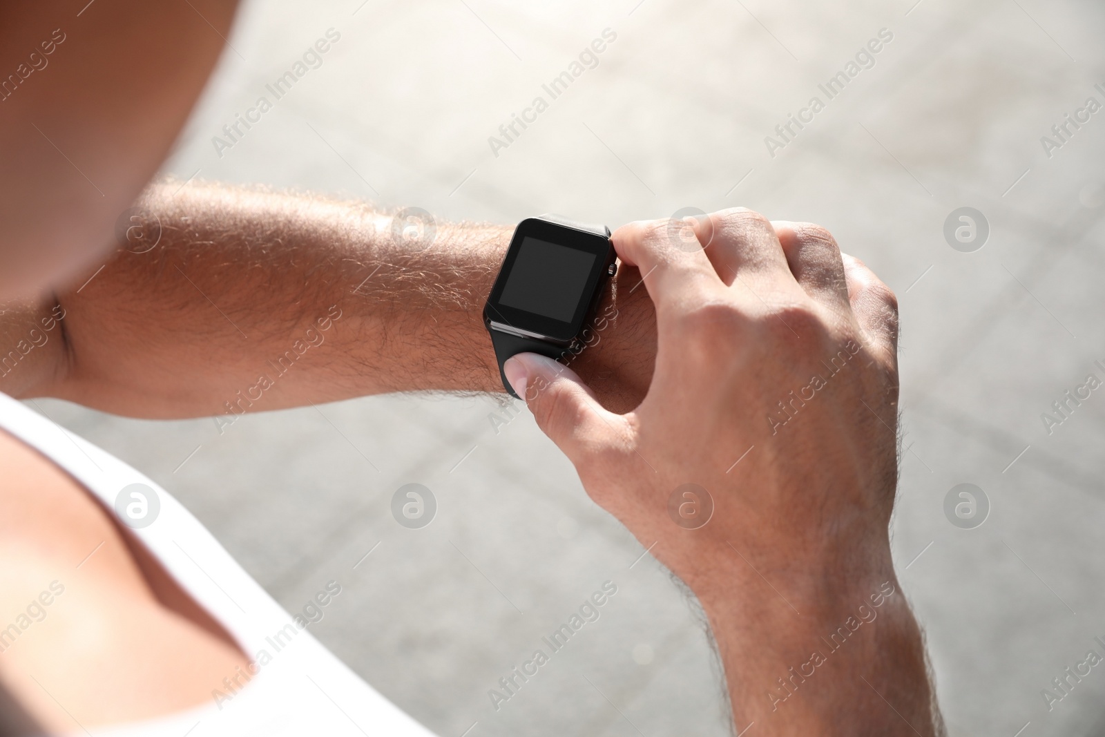 Photo of Man checking fitness tracker after training outdoors, closeup