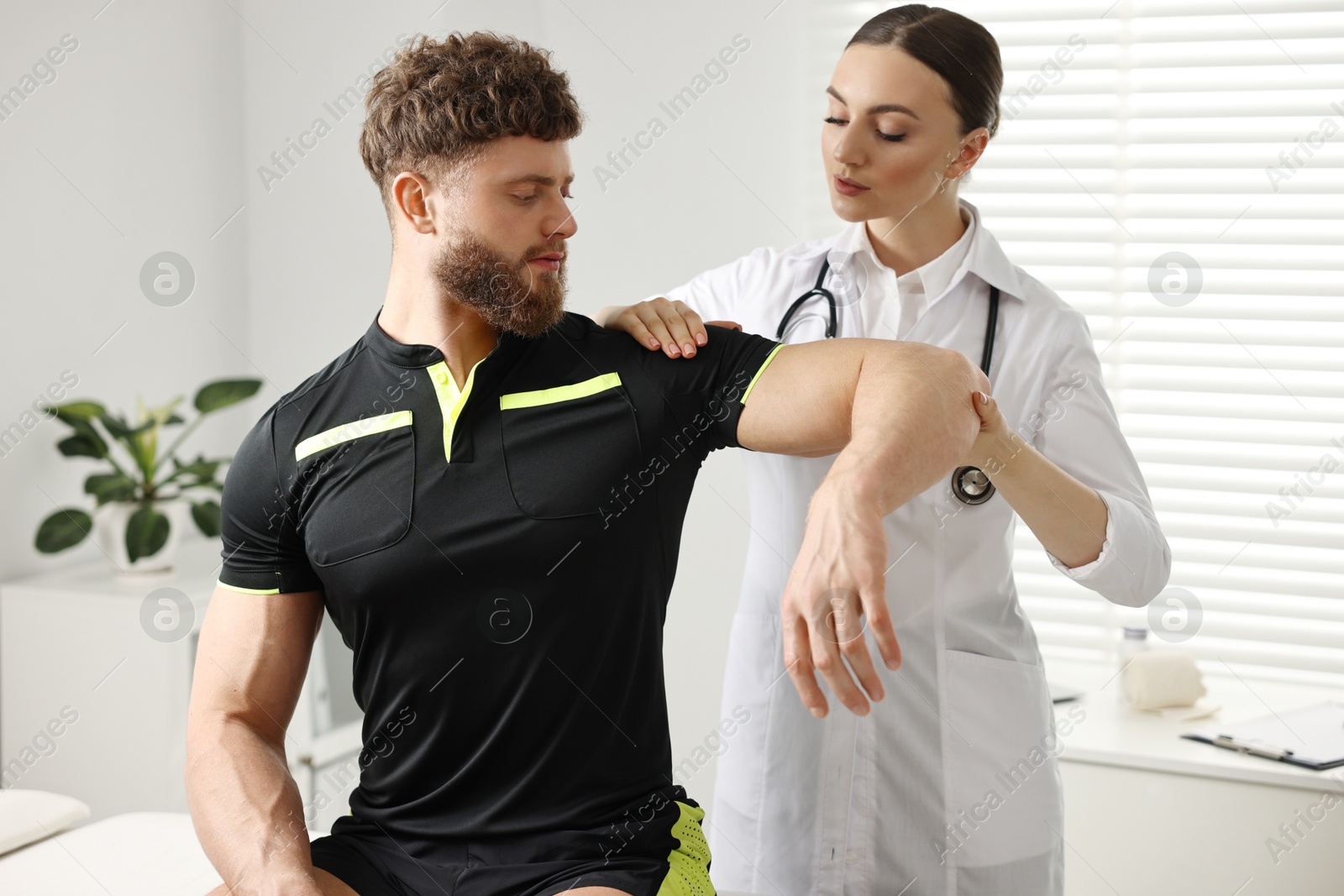 Photo of Sports injury. Doctor examining patient's shoulder in hospital