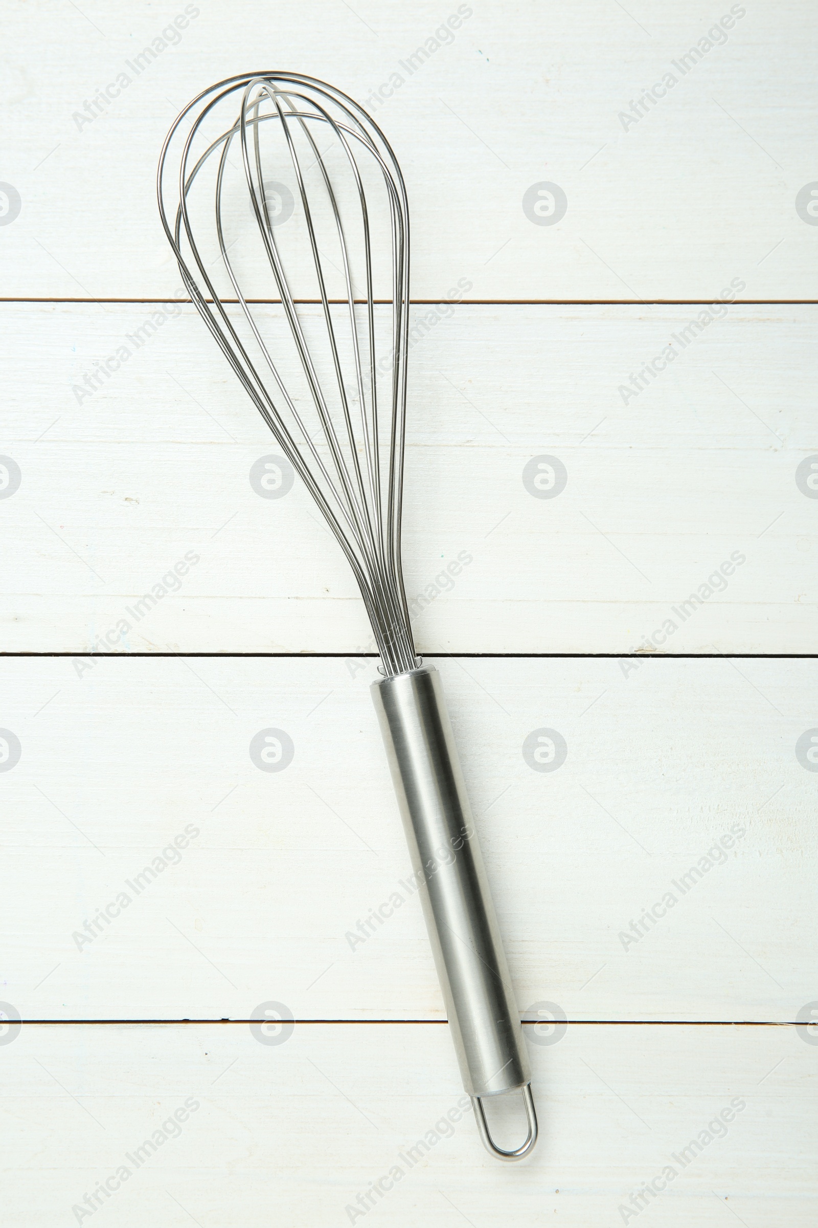 Photo of Metal whisk on white wooden table, top view