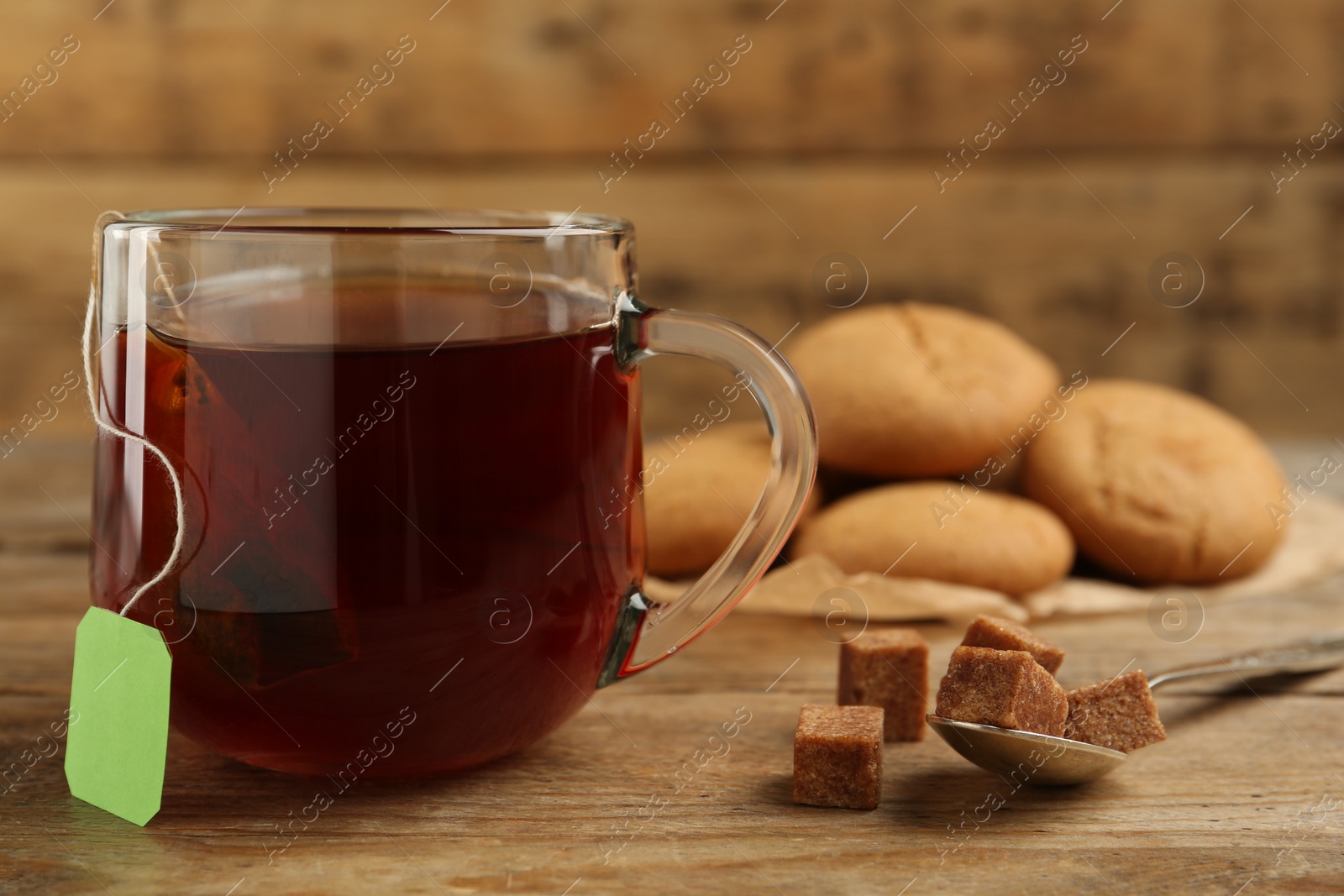 Photo of Tea bag in glass cup of hot water and sugar on wooden table, closeup. Space for text