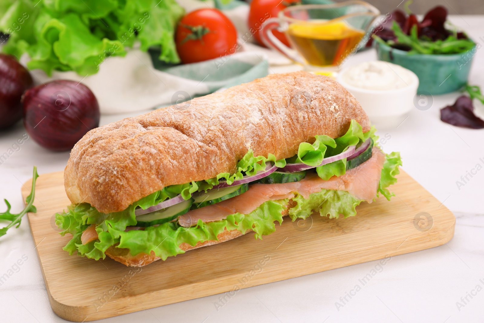 Photo of Delicious sandwich with fresh vegetables and salmon on white table, closeup