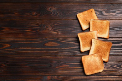 Photo of Slices of tasty toasted bread on wooden table, flat lay. Space for text