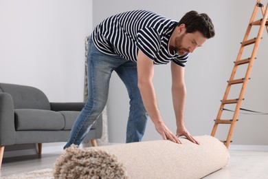 Man unrolling new clean carpet in room