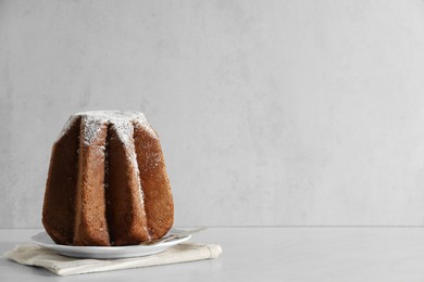 Delicious Pandoro cake decorated with powdered sugar on white table, space for text. Traditional Italian pastry