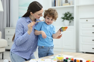 Photo of Mother and her little son painting with palms at home