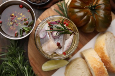 Tasty marinated fish with onion and rosemary in jar on wooden table, flat lay