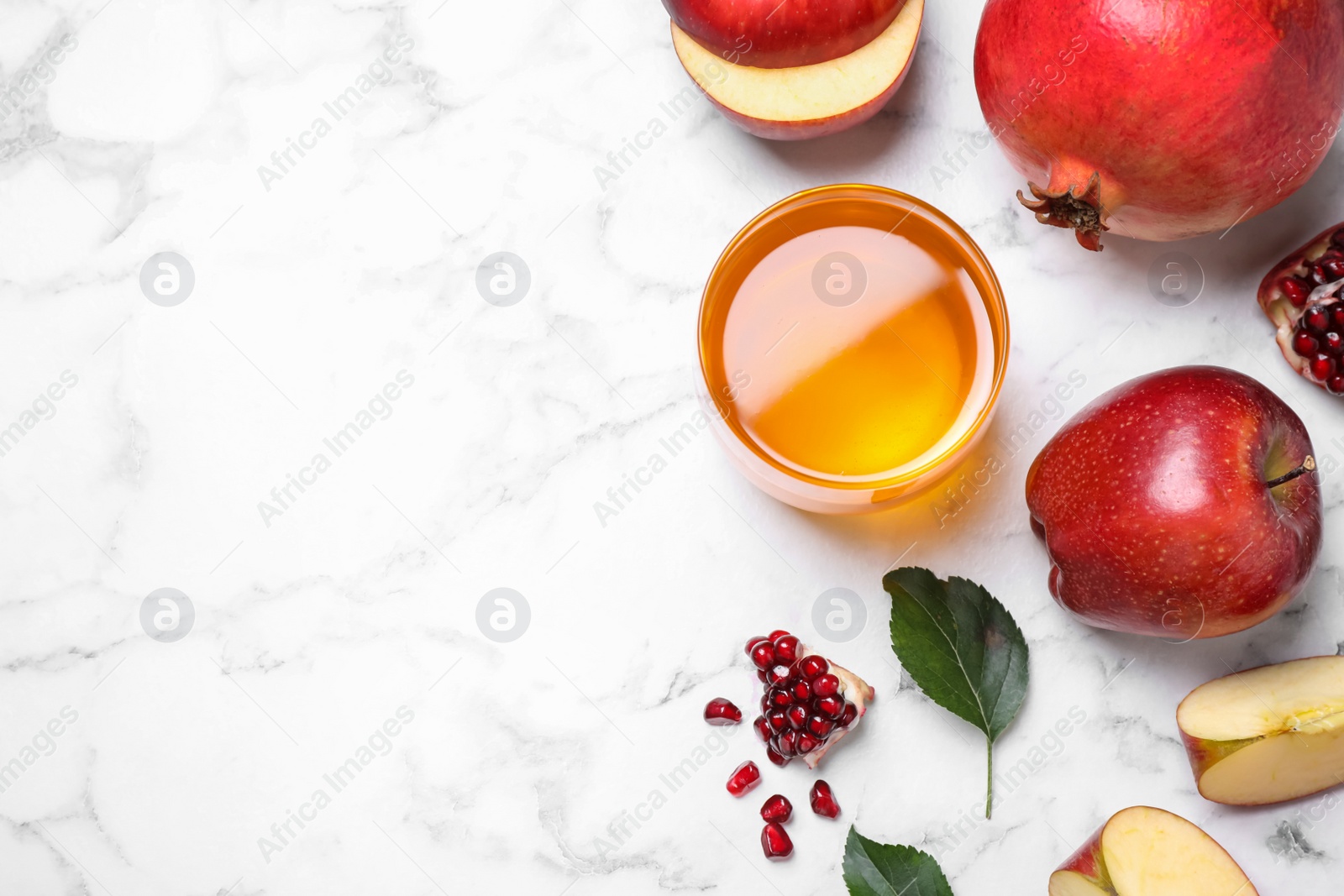 Photo of Honey, apples and pomegranates on white marble table, flat lay with space for text. Rosh Hashanah holiday