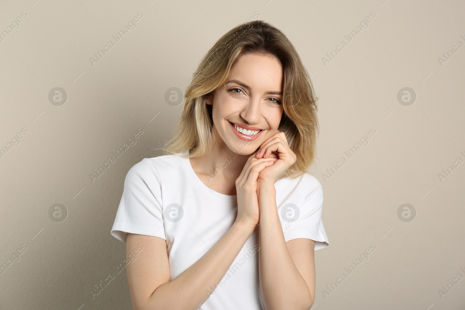 Photo of Portrait of happy young woman with beautiful blonde hair and charming smile on beige background