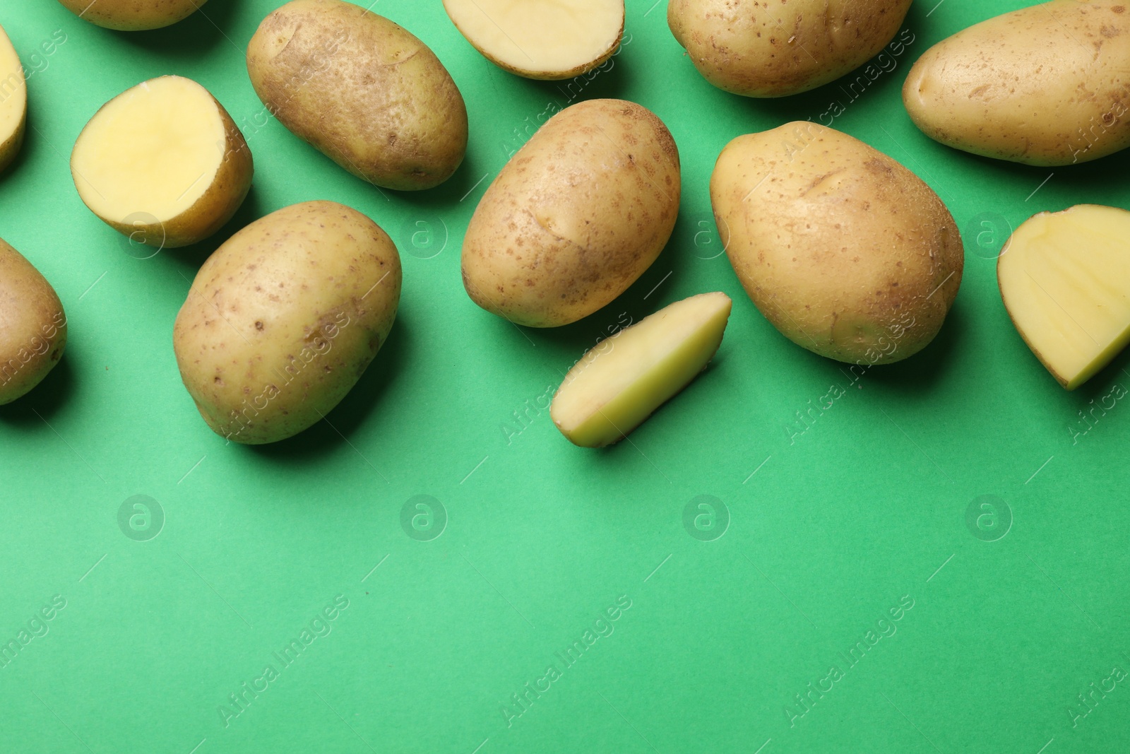 Photo of Fresh raw potatoes on green background, flat lay. Space for text