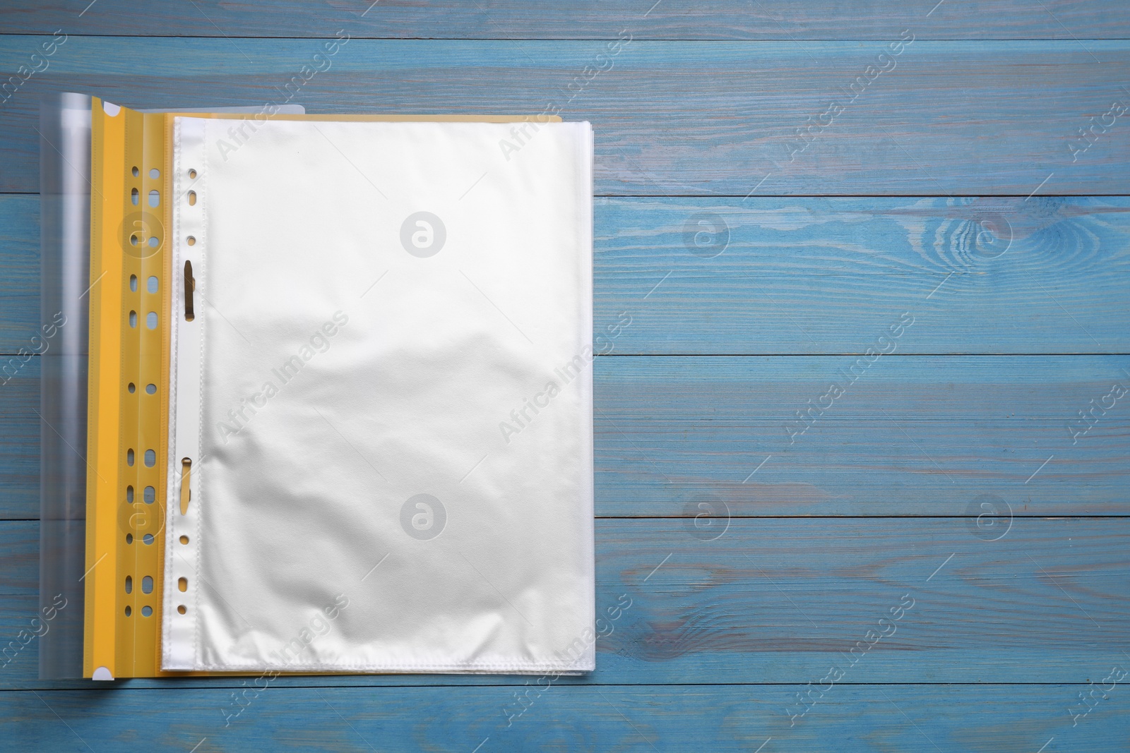 Photo of File folder with punched pockets on light blue wooden table, top view. Space for text