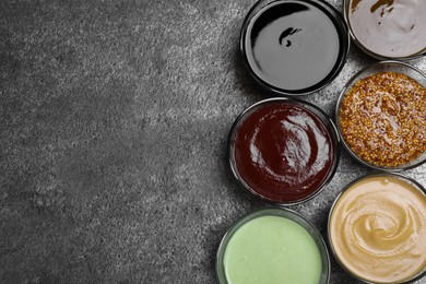 Photo of Many different sauces on grey table, flat lay. Space for text