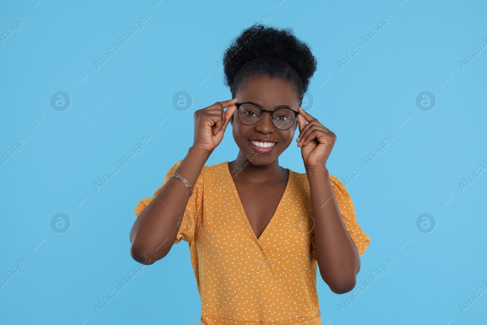 Photo of Portrait of beautiful young woman in eyeglasses on light blue background