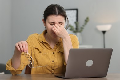 Photo of Overwhelmed woman sitting with laptop at table indoors