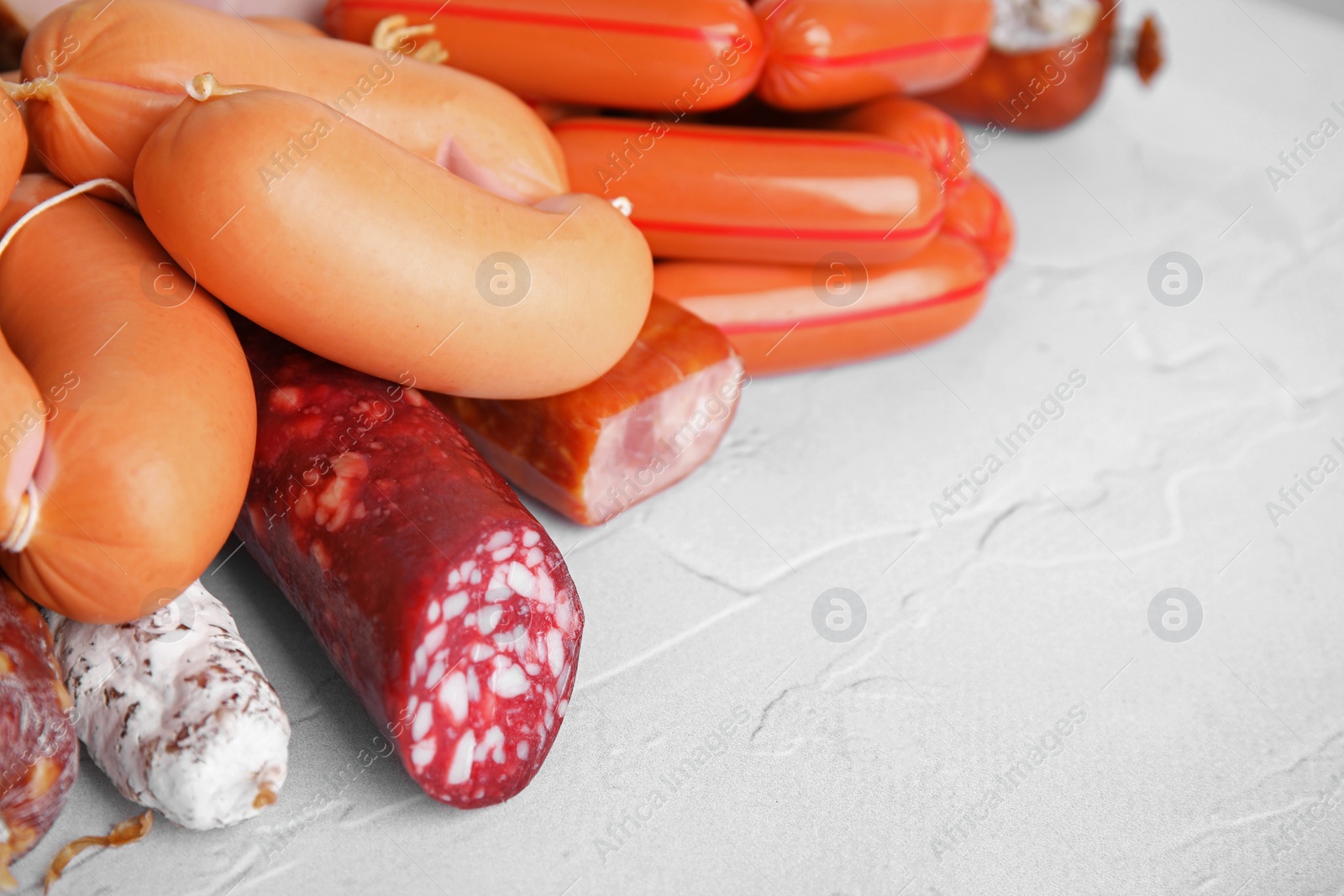 Photo of Different types of sausages on light textured table, closeup. Space for text