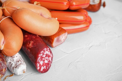 Photo of Different types of sausages on light textured table, closeup. Space for text