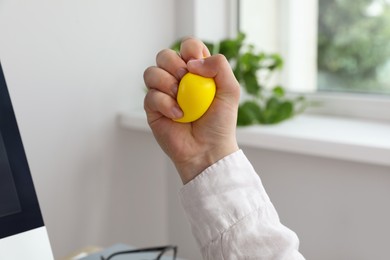 Photo of Man squeezing yellow stress ball in office, closeup