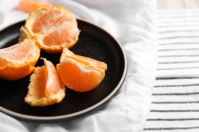 Photo of Fresh ripe tangerines on striped cloth, closeup. Space for text
