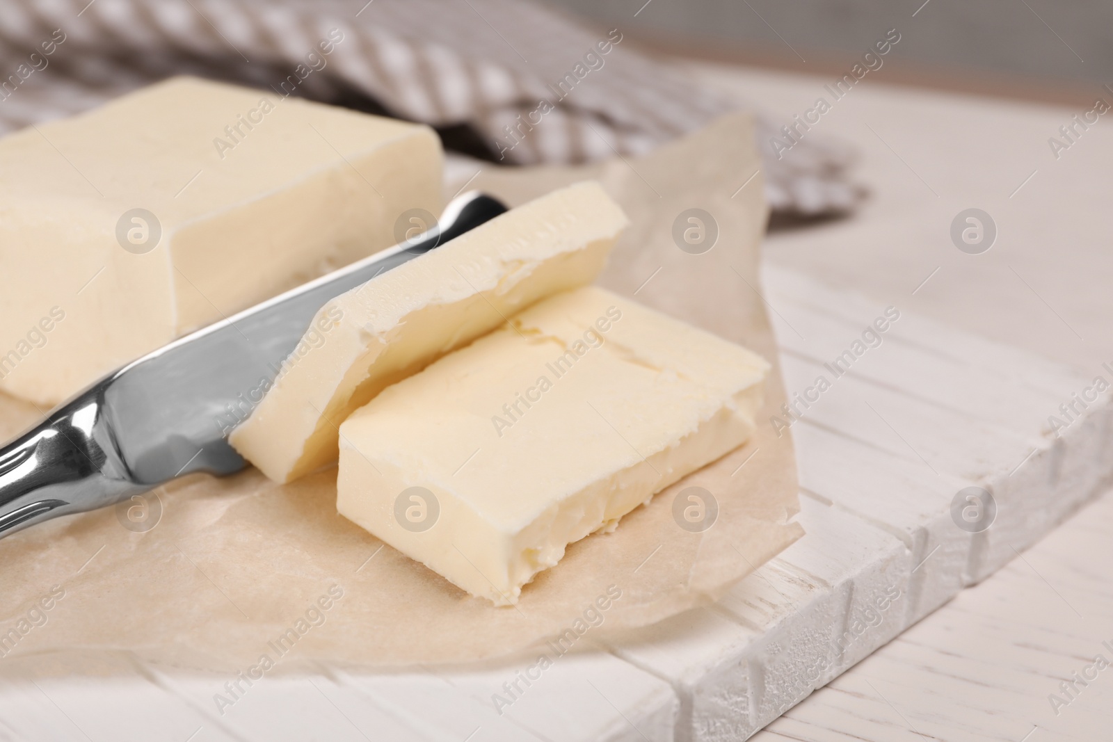 Photo of Cutting tasty fresh butter on wooden board, closeup