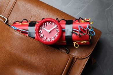 Leather briefcase with dynamite time bomb on grey table, top view