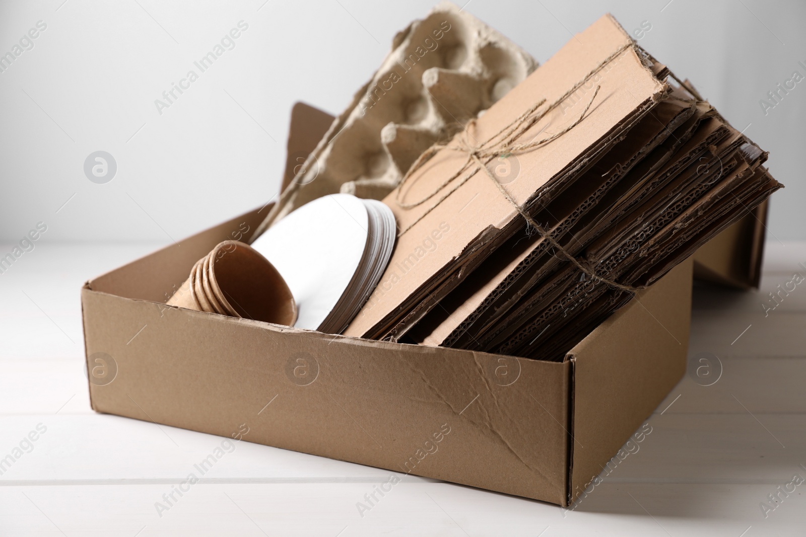 Photo of Box of waste paper on white wooden table