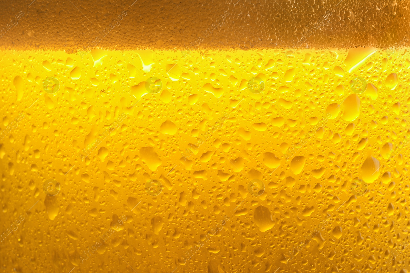 Photo of Glass of tasty cold beer with foam and condensation drops as background, closeup