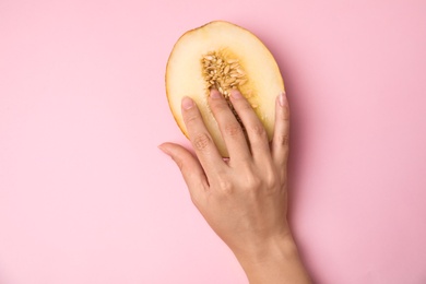 Photo of Young woman touching half of melon on pink background, top view. Sex concept