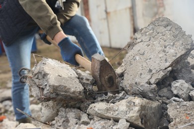 Photo of Man breaking stones with sledgehammer outdoors, closeup