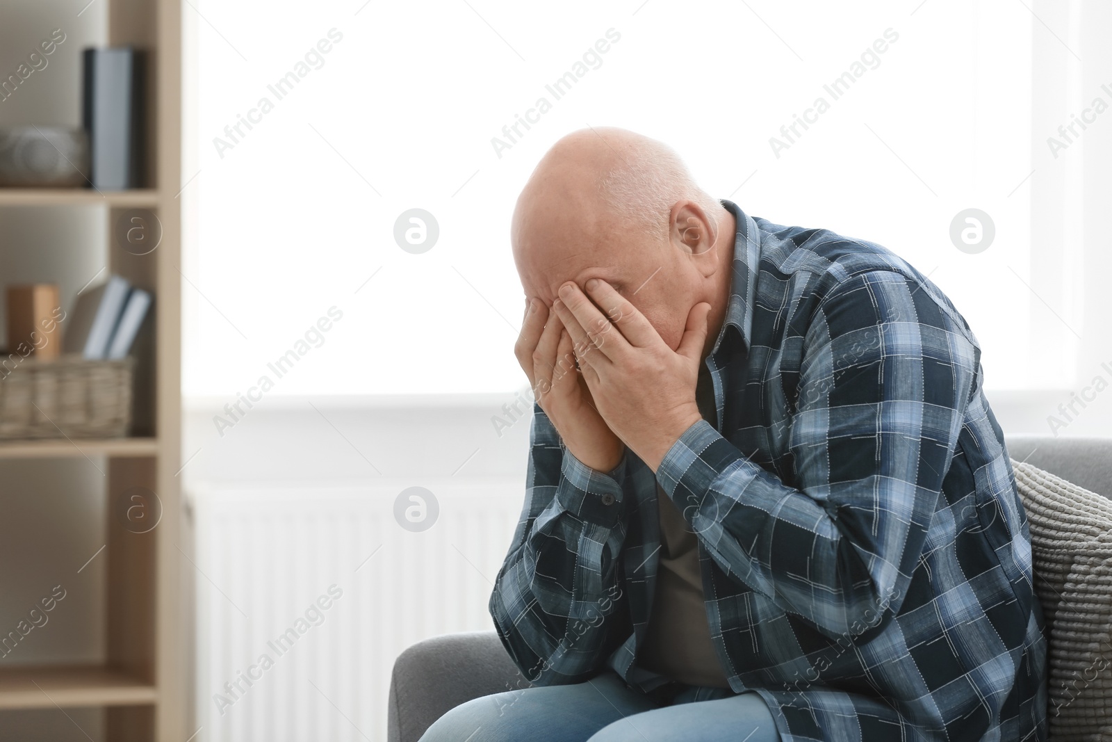 Photo of Depressed senior man sitting on sofa indoors