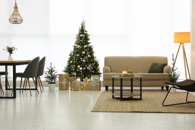 Photo of Beautiful Christmas tree and sofa in contemporary living room. Interior design