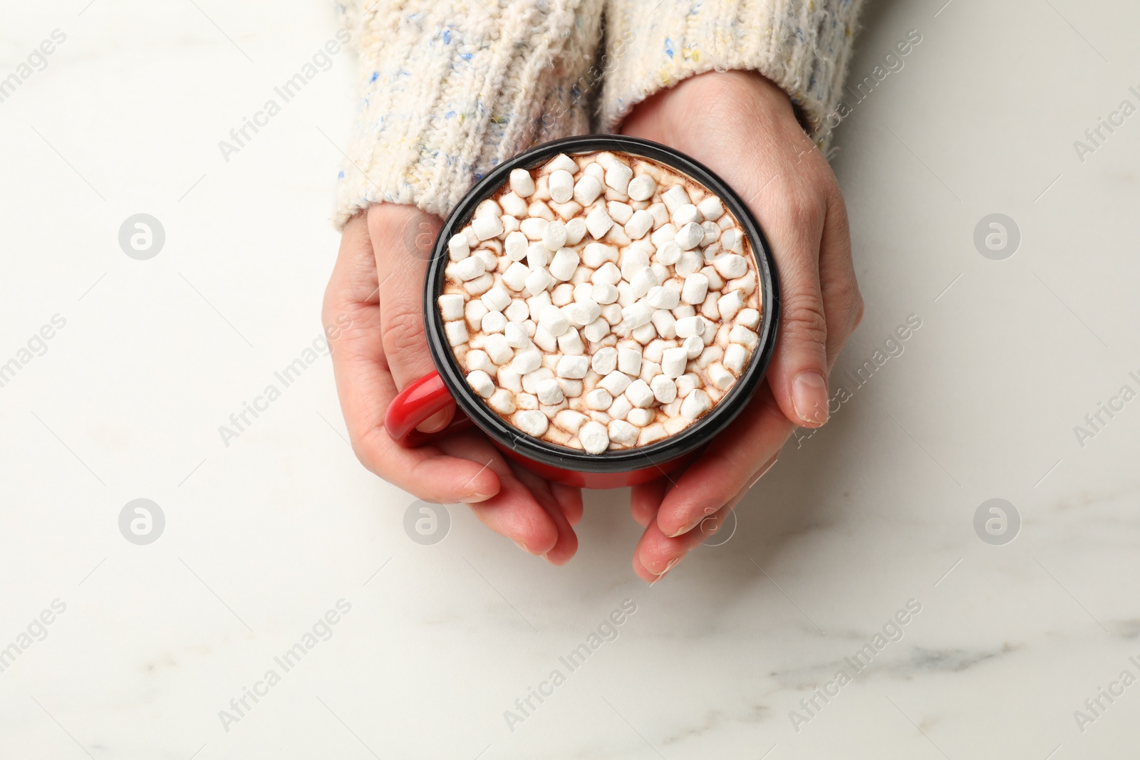 Photo of Woman with cup of tasty hot chocolate and marshmallows at white marble table, top view