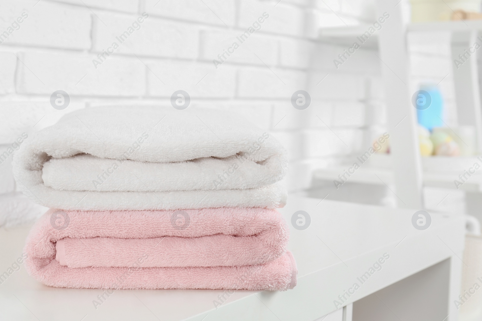 Photo of Stack of fresh towels on table in bathroom. Space for text