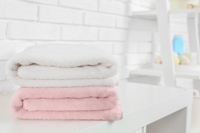 Stack of fresh towels on table in bathroom. Space for text