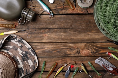 Photo of Flat lay composition with fishing equipment and space for text on wooden background