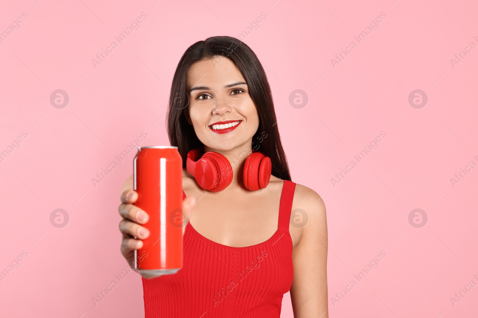 Photo of Beautiful young woman holding tin can with beverage on pink background