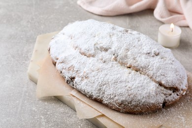 Photo of Delicious Stollen sprinkled with powdered sugar on light table, closeup