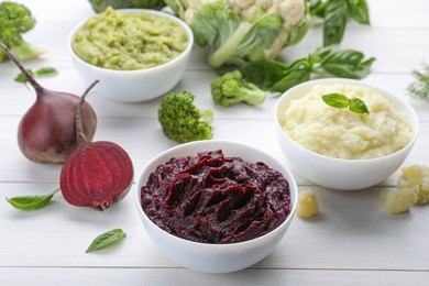Photo of Bowls with different tasty puree and ingredients on white wooden table